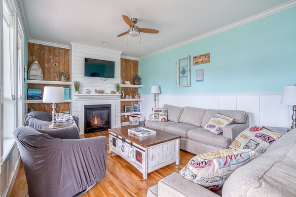 Settle into this coastal-inspired living room where soft sea hues meet cozy comfort. You'll love the warmth of the fireplace, plush seating, and nautical touches that create your perfect retreat.