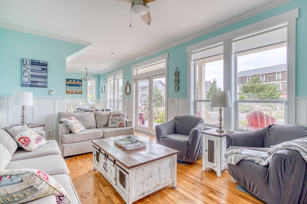 Sink into plush seating in your bright coastal living room, where soft sea-foam walls and sunny windows frame your peaceful neighborhood retreat.